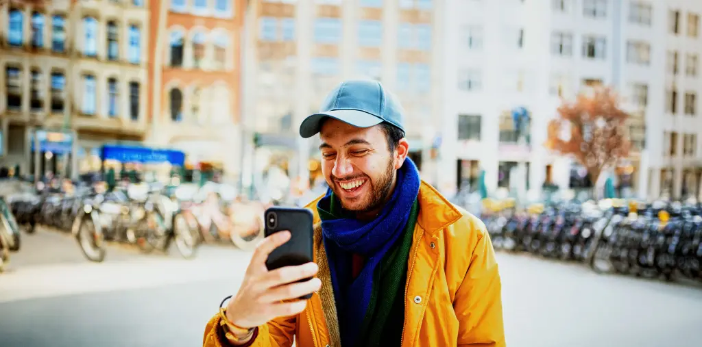 Hombre con gorra riendo mientras mira el móvil
