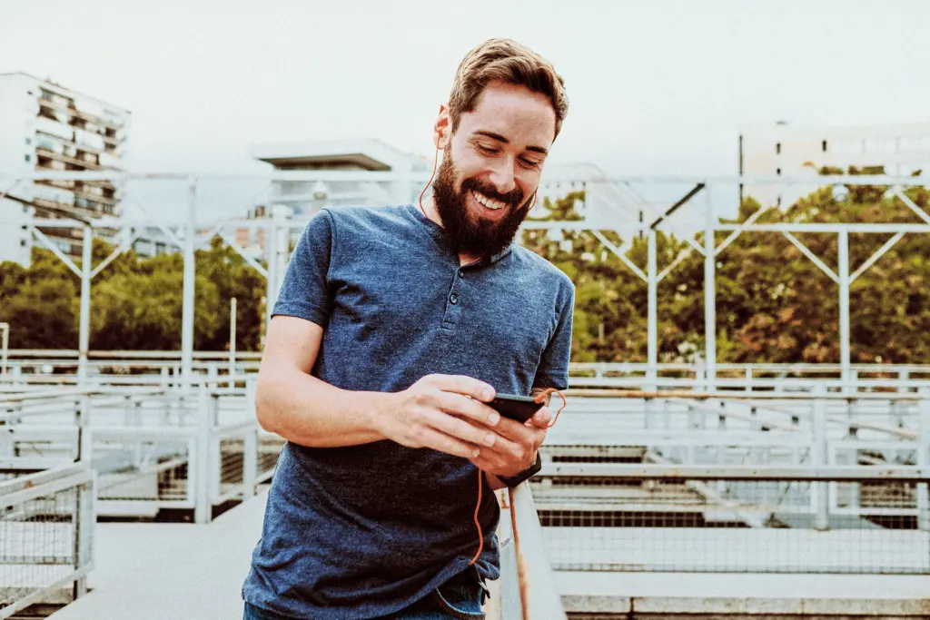 Hombre sonriente con camiseta azul mirando el movil