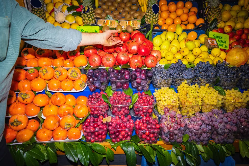 Variedad de frutas y una mano cogiendo tomates