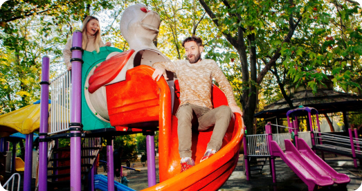 Dos amigos tirándose por el tobogán de un parque