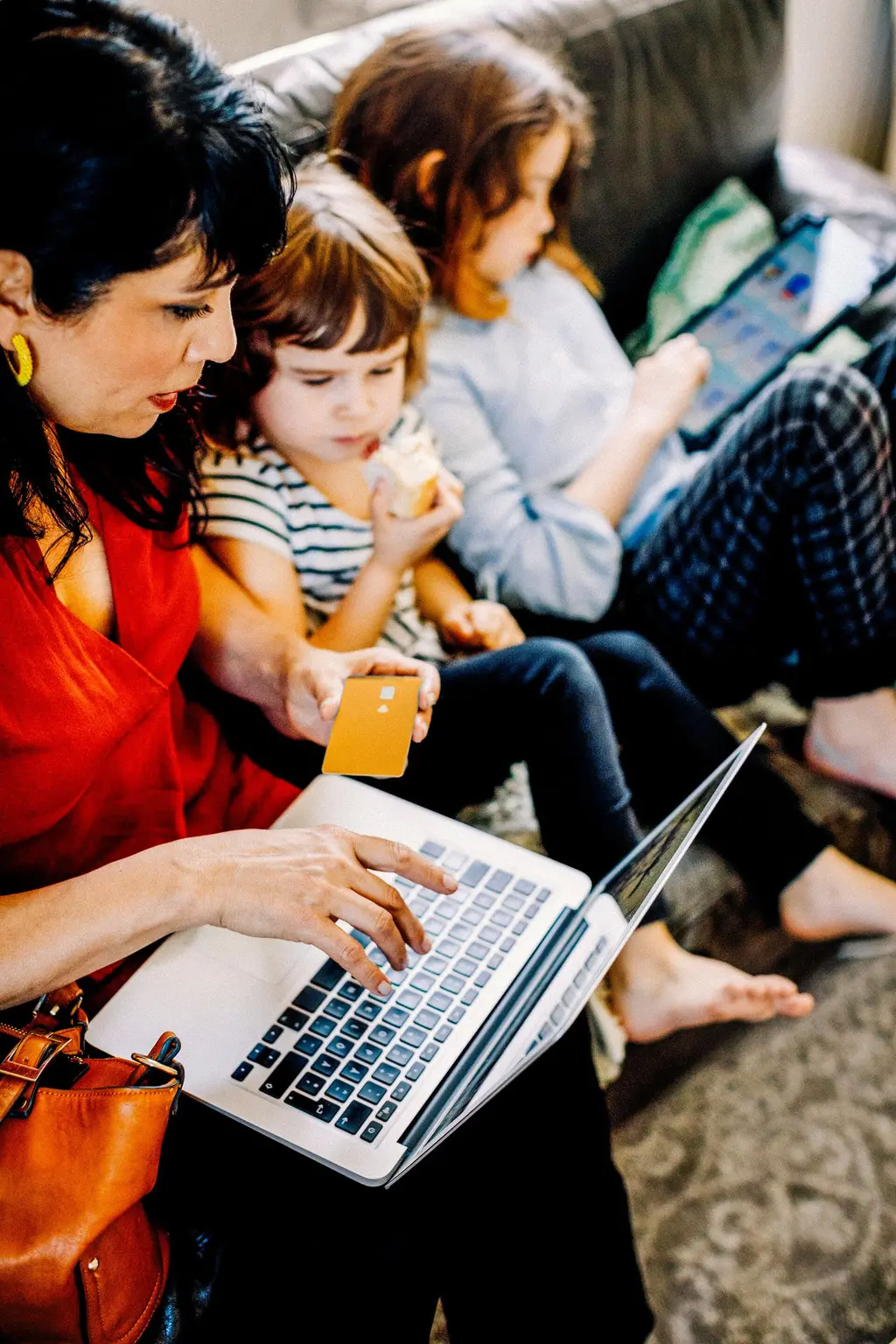 Mujer sonriendo mientras paga con tarjeta online con hijo