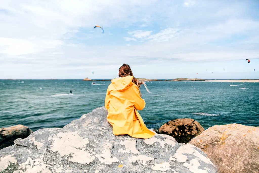 Chica en un espigón de la playa con chubasquero amarillo