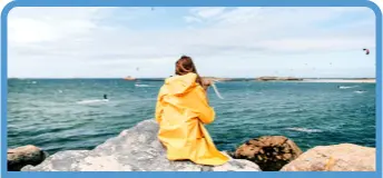 Chica en un espigón de la playa con chubasquero amarillo