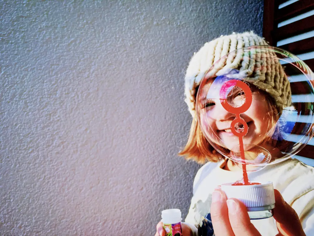 Niña con una pompa de jabón