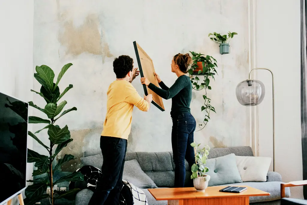 Pareja colocando un cuadro en la pared