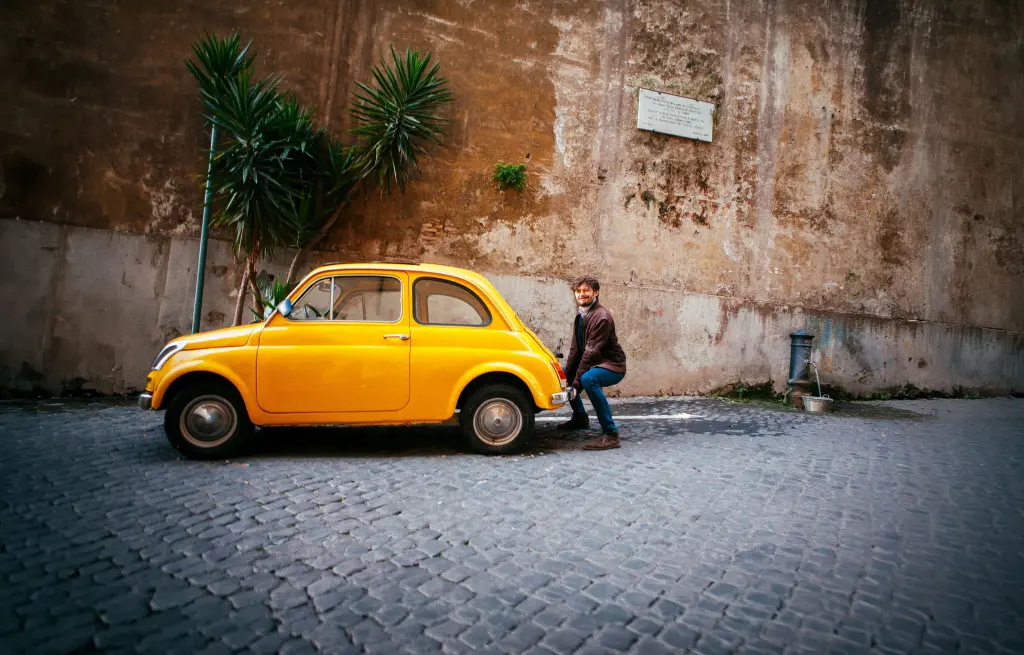 Hombre intentando levantar un coche amarillo