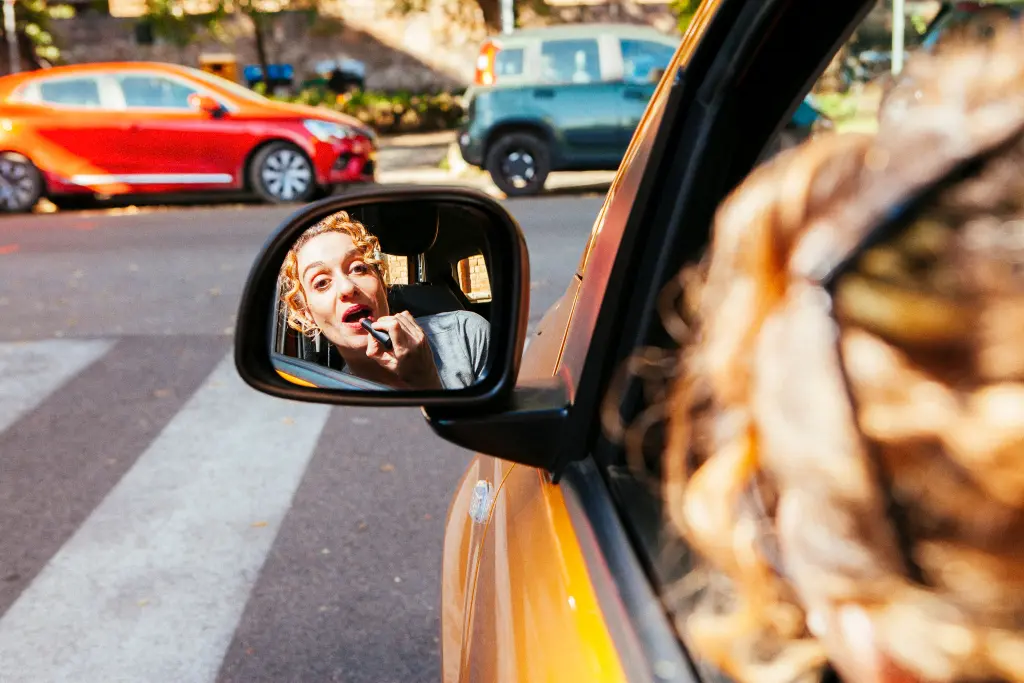 Chica maquillandose en el coche con el retrovisor